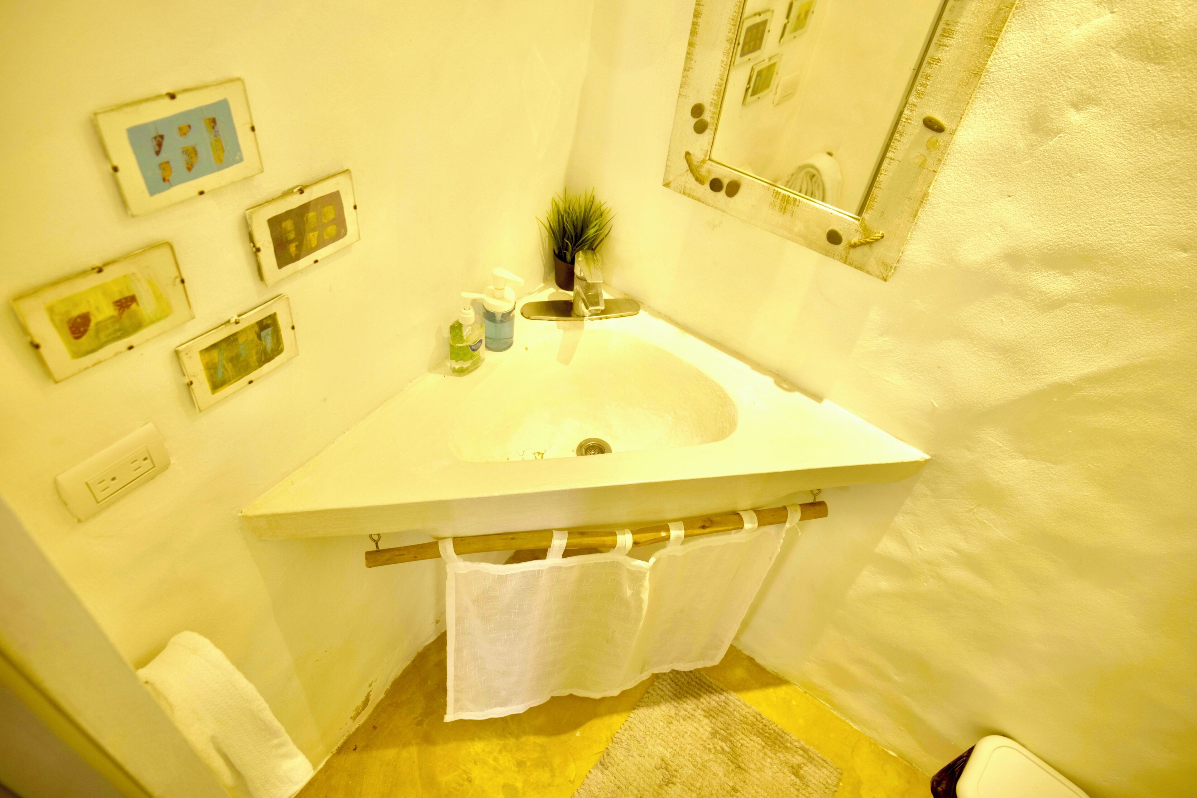 Un bagno con lavandino, specchio e diverse foto appese alle pareti.