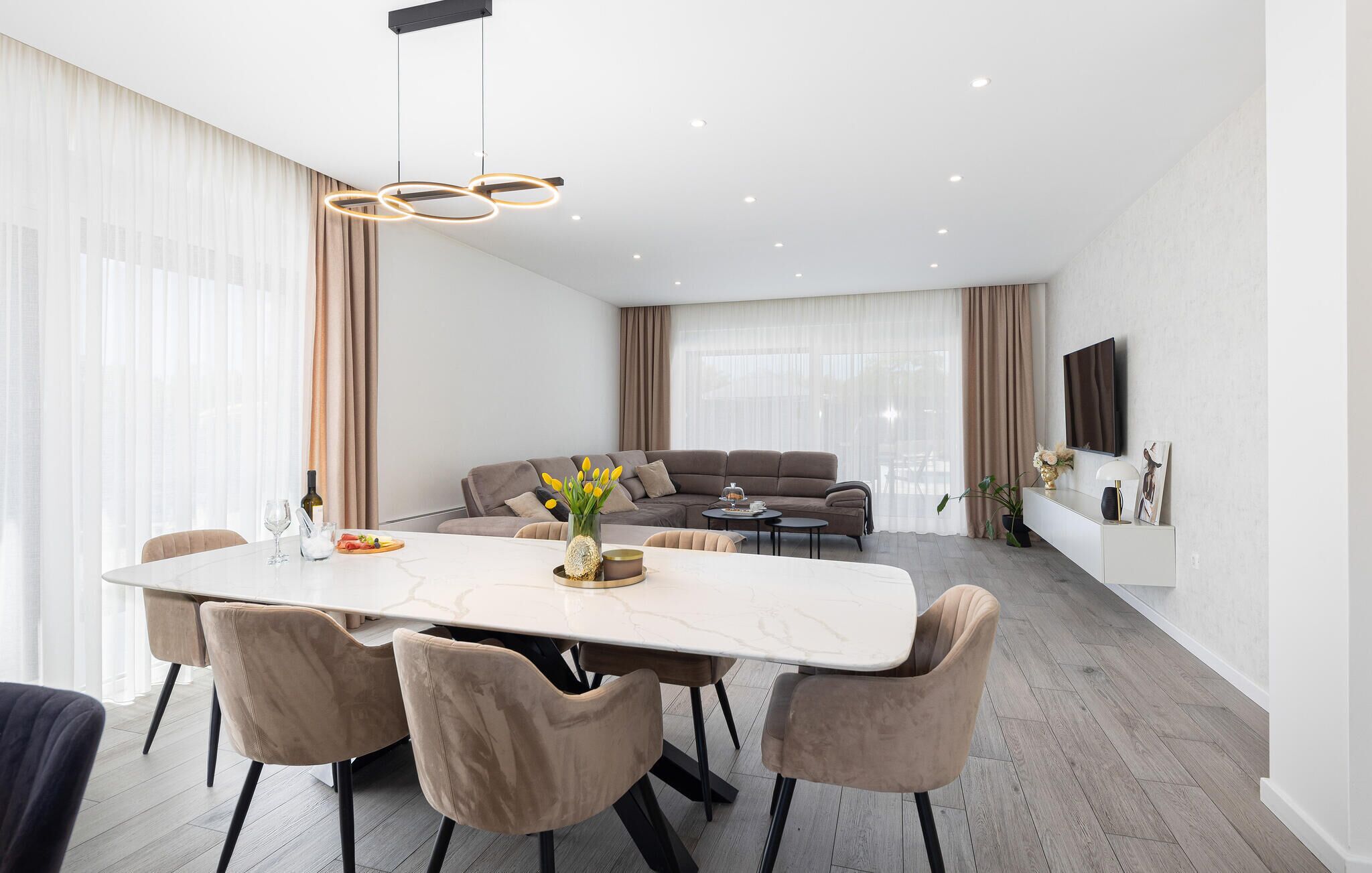A modern living room with a dining area, featuring a large table, comfortable seating, and a sofa.