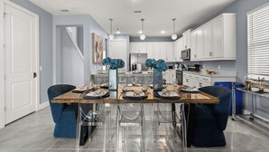 Eine moderne Küche mit weißen Schränken, einem Holztisch und blauen Stühlen.