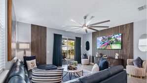 Ein modernes Wohnzimmer mit einem schwarzen Ledersofa, einem runden Couchtisch und einem an der Wand befestigten Fernseher.
