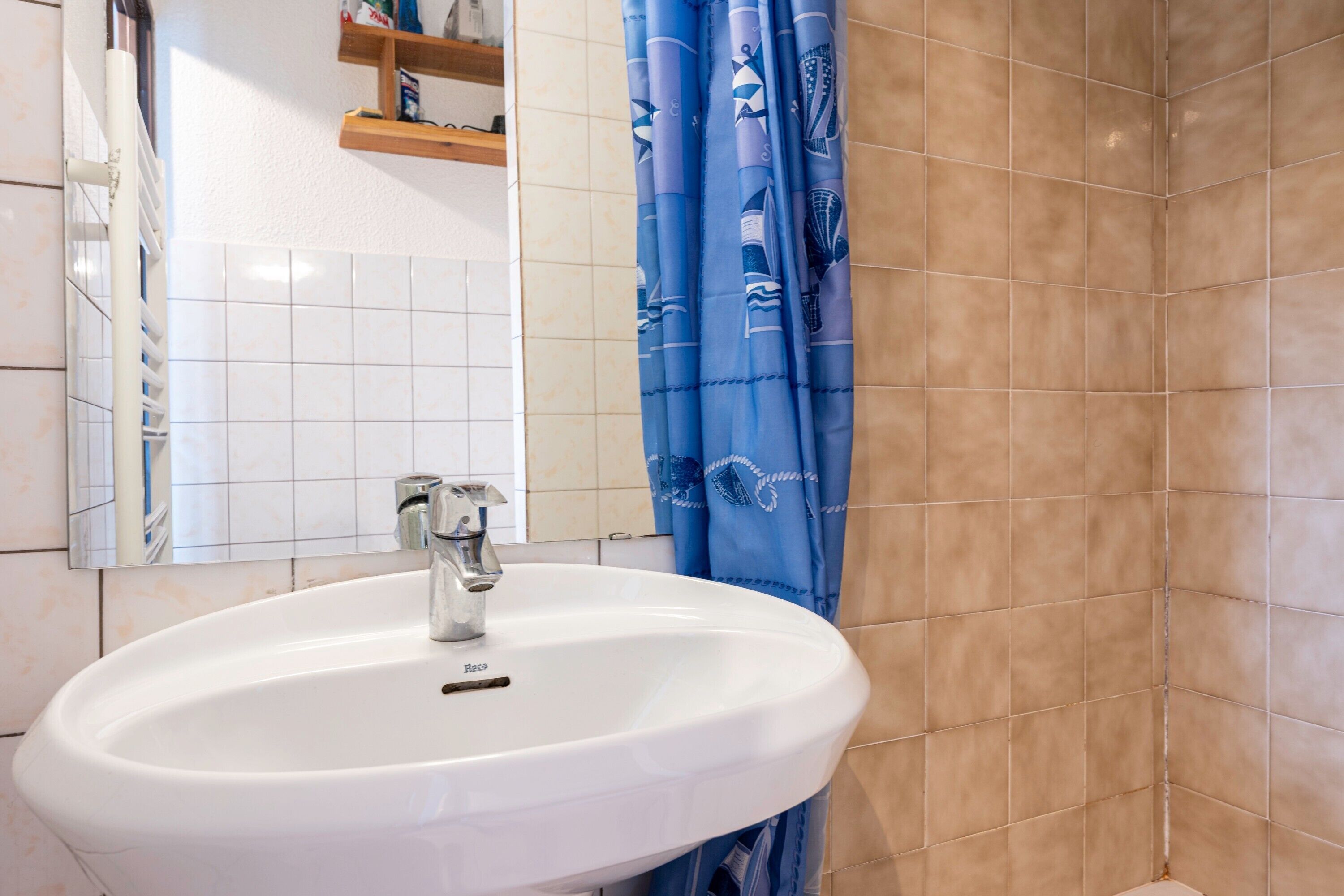 A bathroom with a white sink, a mirror, and a blue shower curtain.