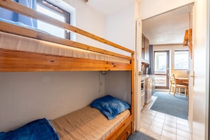 A bunk bed room with a kitchen area visible through an open door.