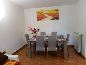 A dining area with a table, chairs, a vase of flowers, and a painting on the wall. - Apartment 'La Casina Nel Borgo' with Mountain View, Private Terrace and Wi-Fi (Cetona)