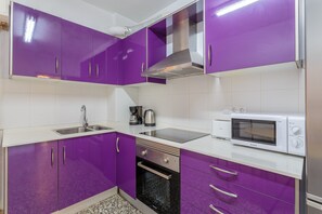 A kitchen with purple cabinets, a stainless steel sink, a microwave, and a stove. - Apartment 'Staffan En Santa Pola' with Sea View, Wi-Fi and Air Conditioning (Santa Pola)