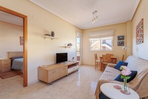 Ein Wohnzimmer mit einer Couch, einem Fernseher und einem Essbereich mit Stühlen.