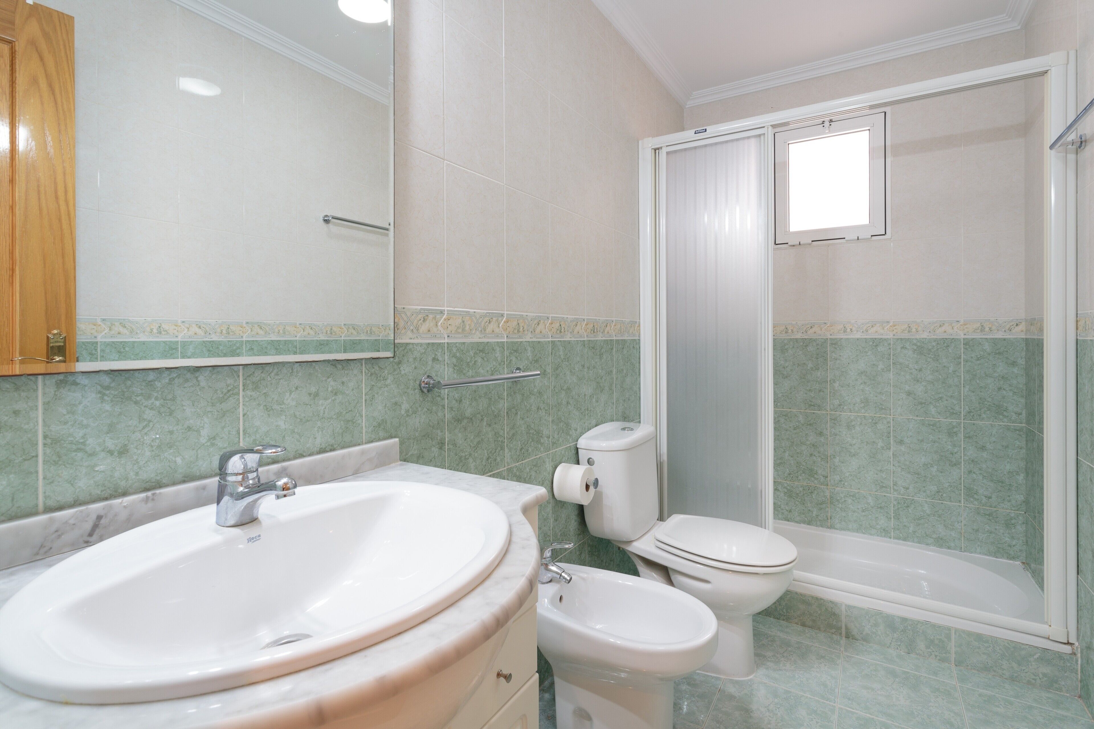 A bathroom with a sink, toilet, bidet, and shower.