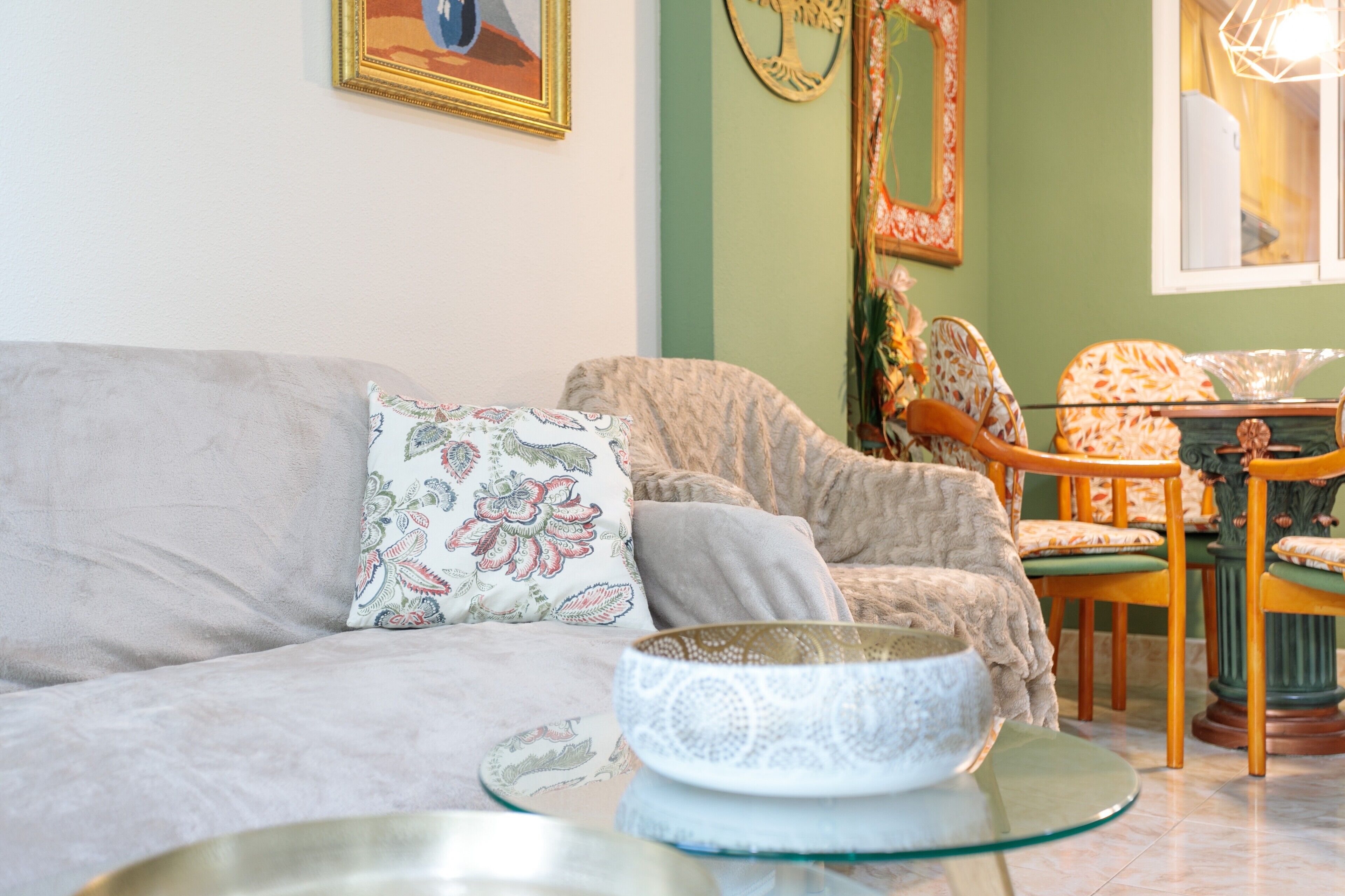 A living room with a sofa, chairs, a glass coffee table, and decorative items.