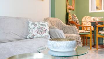 A living room with a sofa, chairs, a glass coffee table, and decorative items.