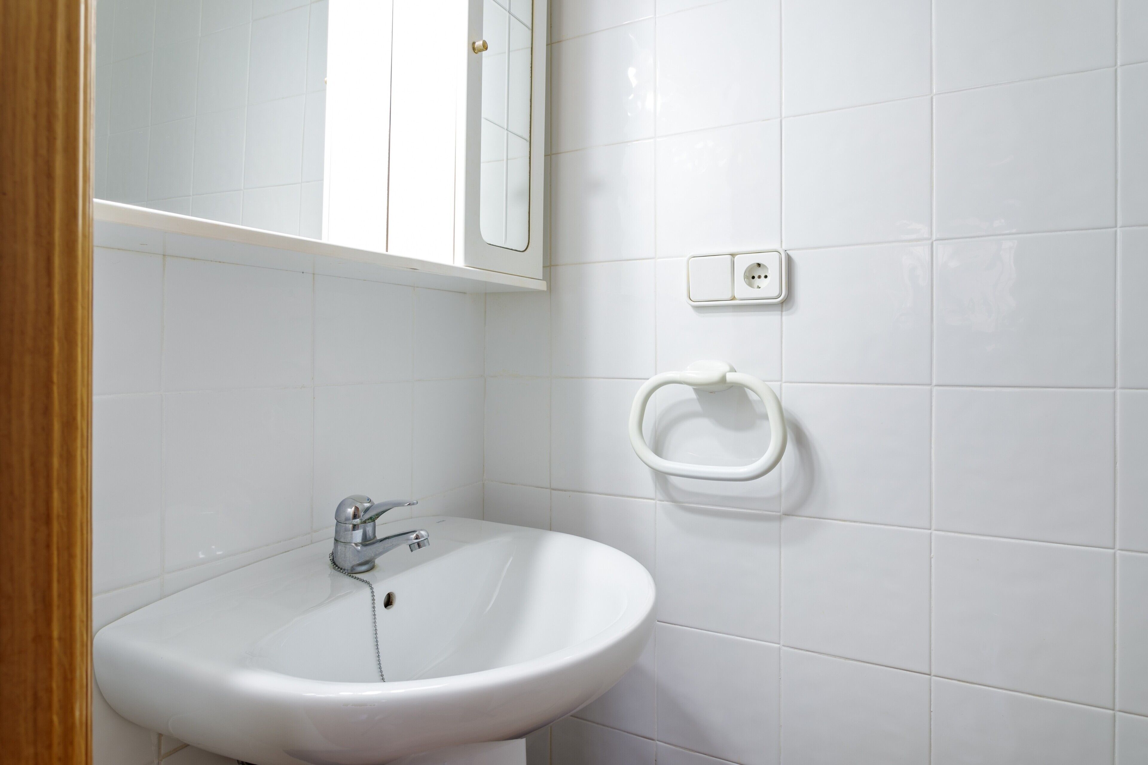 Ein Badezimmer mit einem weißen Waschbecken, einem Spiegel und einem Handtuchhalter an der Wand.