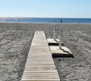 Un sendero de madera que conduce a una playa con dos postes blancos marcados con números.