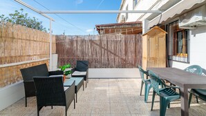 Um pátio com móveis de exterior, uma mesa de madeira e uma vedação de bambu.