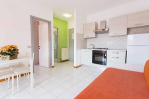 Un espacio habitable compacto con kitchenette, zona de comedor y cama.