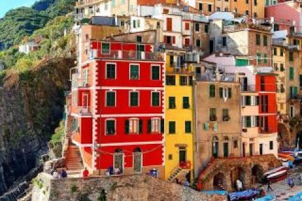 Un edificio costero colorido con varios balcones y un acantilado rocoso y empinado.