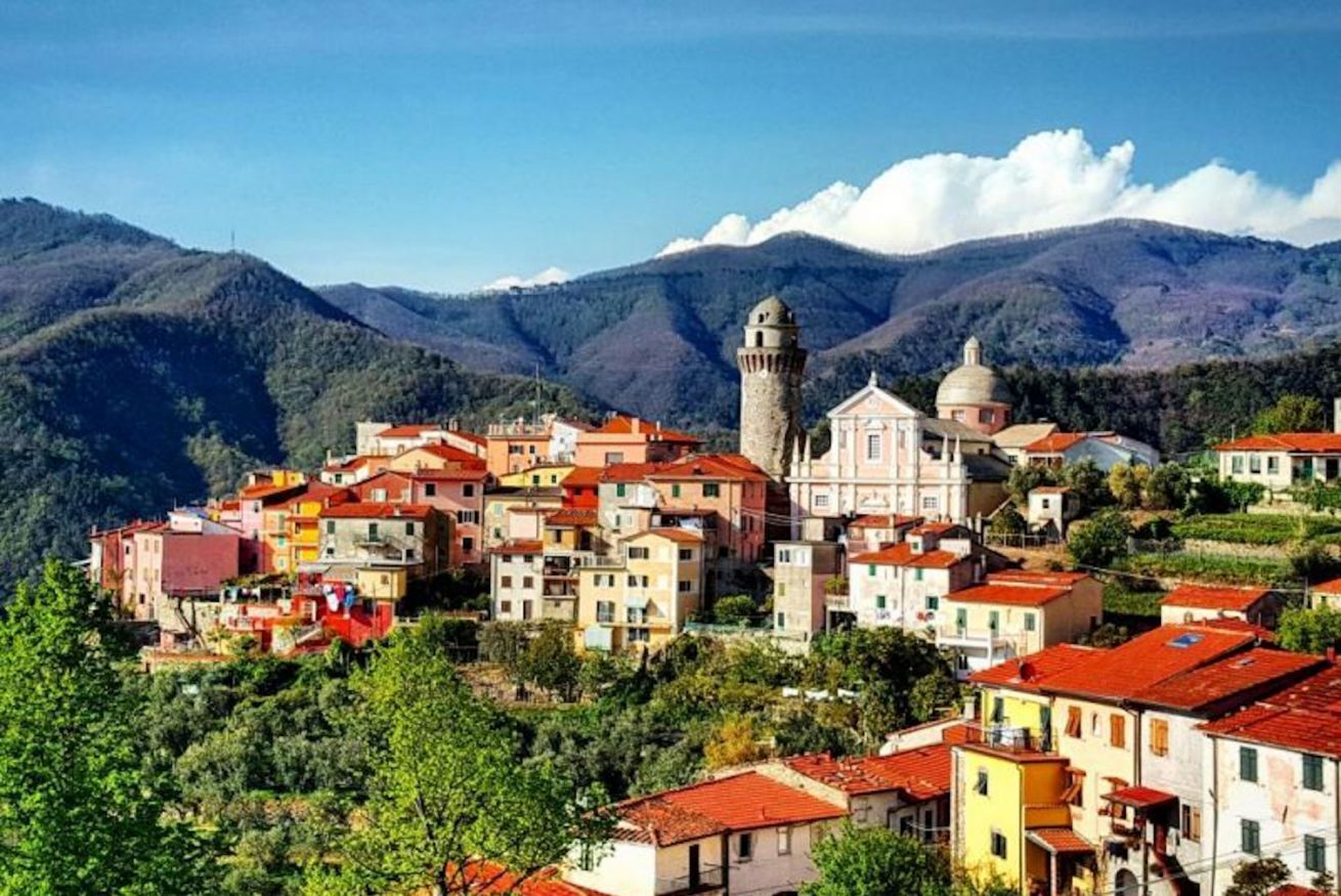 A hillside village with colorful buildings and a prominent tower.