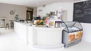 A modern bar area with a white counter, a coffee machine, and a chalkboard menu. - Two-room apartment of 45 sqm, consisting of a large living room/dining area with equipped kitchenette and sofa bed with 2 single pull-out beds, a double bedroom, bathroom with shower, private balcony complete with table and chairs.Equipped with:- Air con (Luni Mare)