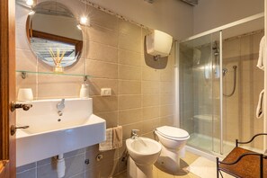 A bathroom with a glass-enclosed shower, a sink with a mirror, and a toilet.