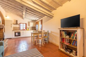 A cozy living room with a fireplace, a dining area with a table and chairs, a bookshelf, and a television.