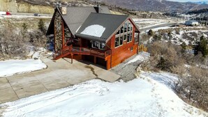 Eine Holzhütte mit geneigtem Dach, großen Fenstern und einem Steinfundament.