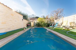A swimming pool with a stone wall, a wooden deck, and a slide. - Holiday Home 'Le Chalet Houda Et Spa En Option' with Private Pool and Air Conditioning (Nîmes)