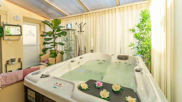 A hot tub with lotus flowers, a clock, and a mirror on the wall.