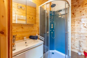 A wooden cabin bathroom with a glass-enclosed shower, a sink, and a towel rack. - Holiday Home 'Le Chalet Houda Et Spa En Option' with Private Pool and Air Conditioning (Nîmes)