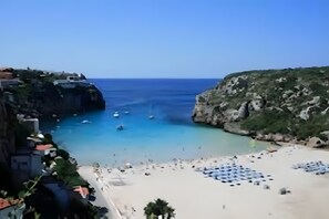 A coastal area with a beach, boats, and rocky cliffs. - Villa 'Las Amapolas' with Private Pool, Wi-Fi and Air Conditioning (Cala en Porter)