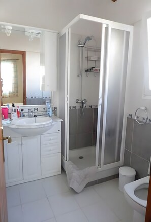 Un baño moderno con cabina de ducha, lavabo e inodoro.