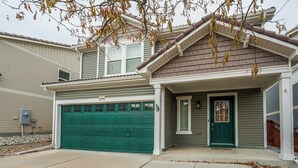 A two-story house with a green garage door, a front porch, and a mailbox. - Quartz Castle (Castle Rock)