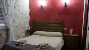 Ein Schlafzimmer mit einem hölzernen Bett, zwei Nachttischen, einer roten Wand und einem Fenster mit weißem Vorhang.