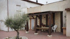 Eine Terrasse mit einer Pergola, einem kleinen Baum und einem Tisch mit Stühlen.