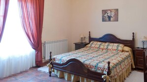 Une chambre à coucher avec un lit, un radiateur, un tableau et un lustre.