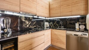 A modern kitchen with wooden cabinets, a black marble backsplash, stainless steel appliances, and a dishwasher. - Country House 'Hortensia' with Mountain View, Private Terrace and Wi-Fi (Asturias)