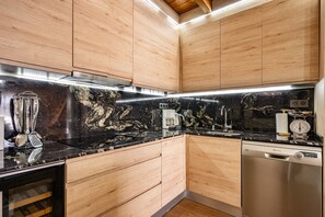 A modern kitchen with wooden cabinets, a black marble backsplash, stainless steel appliances, and a dishwasher. - Country House 'Hortensia' with Mountain View, Private Terrace and Wi-Fi (Asturias)