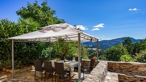 A covered outdoor dining area with stone flooring, metal chairs, and a table set for four. - Country House 'Hortensia' with Mountain View, Private Terrace and Wi-Fi (Asturias)