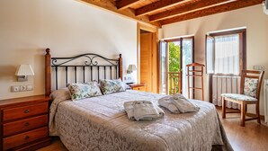 A bedroom with a bed, wooden headboard, bedside tables, a dresser, and a chair. - Country House 'Hortensia' with Mountain View, Private Terrace and Wi-Fi (Asturias)