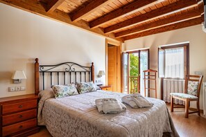A bedroom with a bed, wooden headboard, bedside tables, a dresser, and a chair. - Country House 'Hortensia' with Mountain View, Private Terrace and Wi-Fi (Asturias)