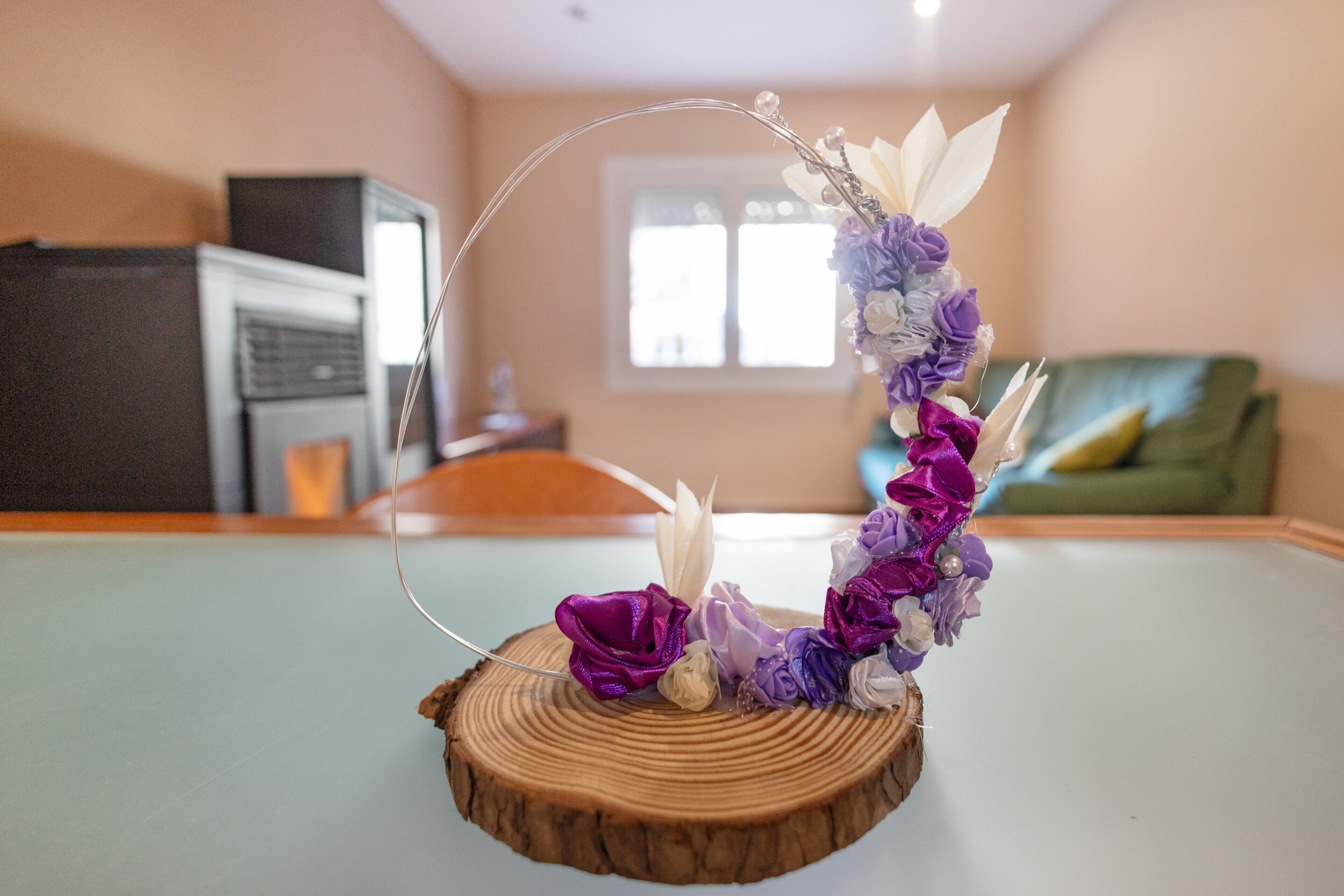 A decorative floral arrangement on a wooden table in a room with a green couch and a window.