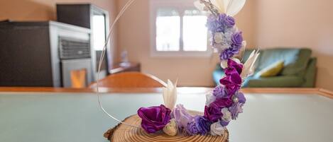 A decorative floral arrangement on a wooden table in a room with a green couch and a window.