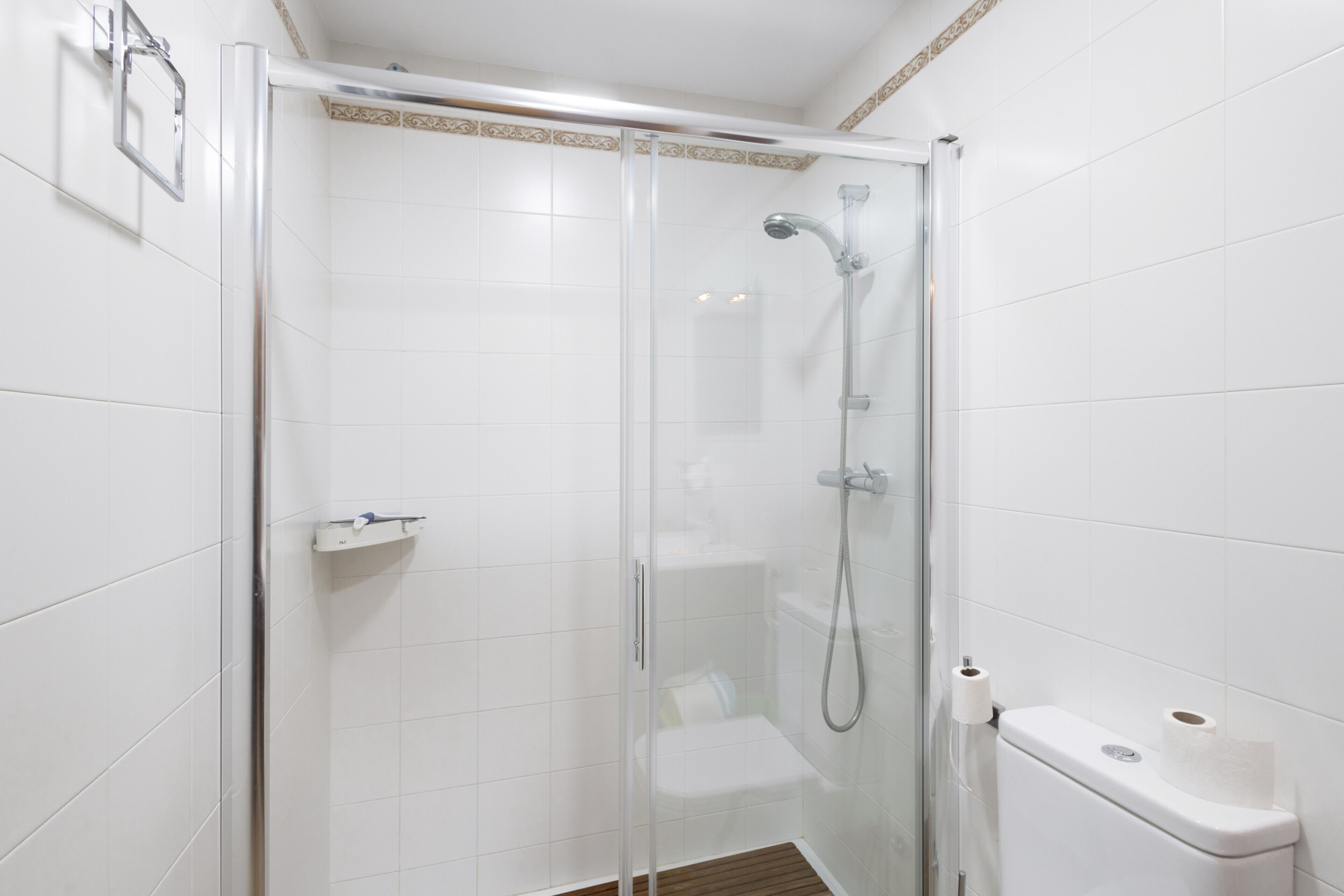 A glass-enclosed shower stall with a toilet and a towel rack.