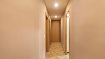 Un pasillo estrecho con puertas de madera a ambos lados, que da a una habitación.