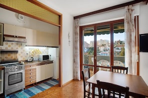 Une cuisine équipée d’une cuisinière, d’un four à micro-ondes et de placards, une table à manger avec des chaises, et une vue par la fenêtre.