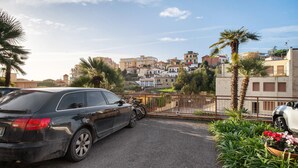 A parking area with a car, a gate, and a building with multiple floors and balconies. - Apartment 'Carla' with Sea View and Balcony (Sanremo)