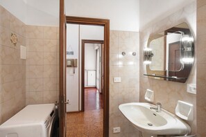 Un baño con lavamanos, espejo y lavadora.