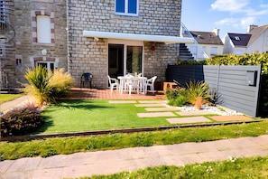 Una casa de piedra con un patio, muebles de exterior y un pequeño jardín.