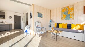 Un salon moderne avec un canapé, un fauteuil, une table basse et une carte accrochée au mur.