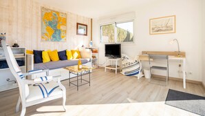 Un salon avec un canapé, un fauteuil, un téléviseur, un bureau et une carte accrochée au mur.