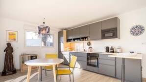 Une cuisine moderne avec des meubles de couleur grise, une table de salle à manger ronde et une statue.