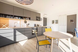A modern kitchen with grey cabinets, a wooden countertop, and a round table with yellow chairs.