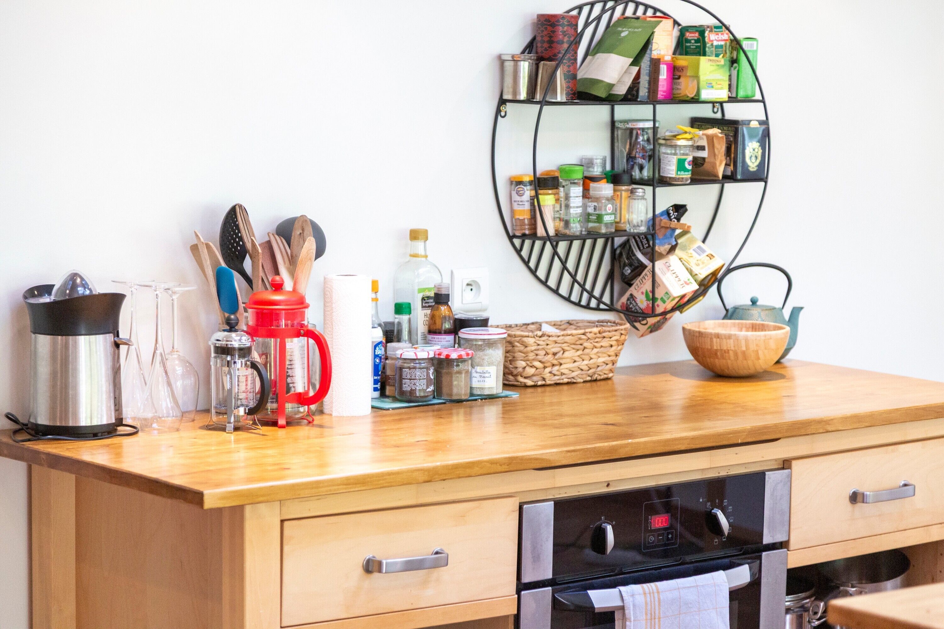 Een keuken met een houten aanrecht, een koffiezetapparaat, een waterkoker en een kruidenrek.