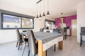 Una cucina moderna con zona pranzo, ampie finestre e una parete decorata in viola.